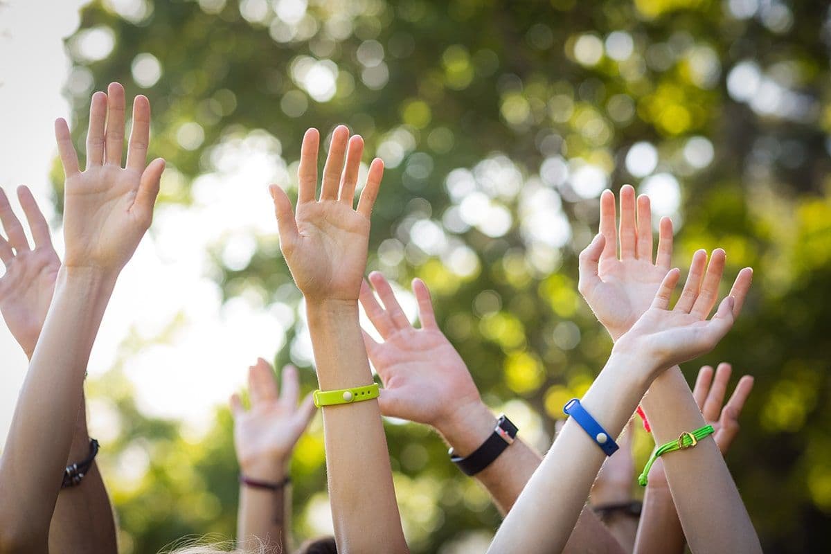 Several hands in the air with wristbands on.